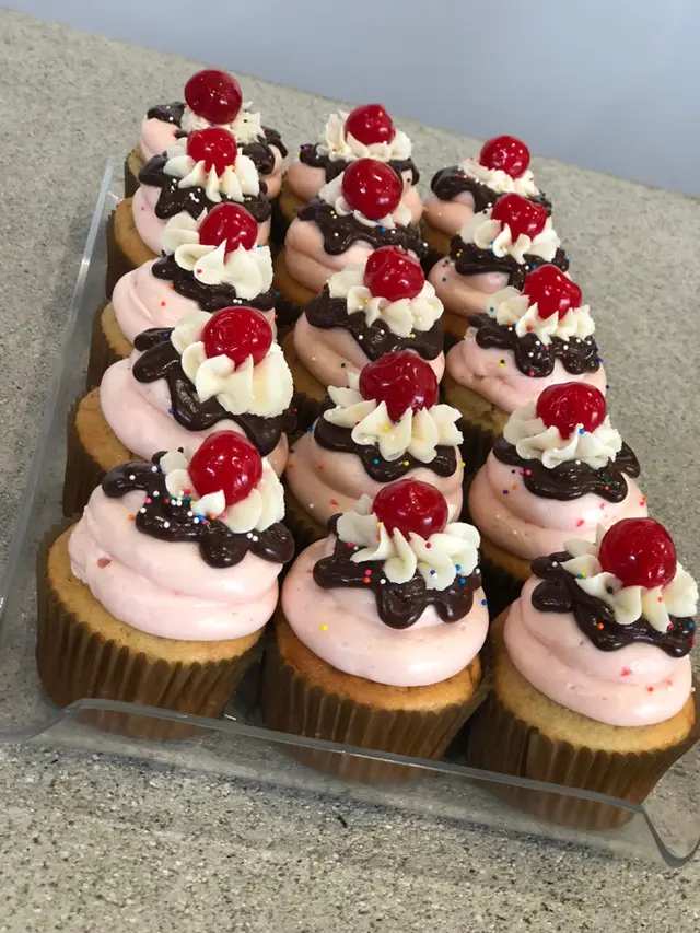 Pink frosted cupcakes topped with cherries