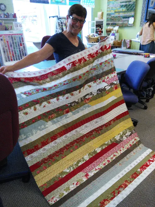 Striped strip quilt held up in the shop
