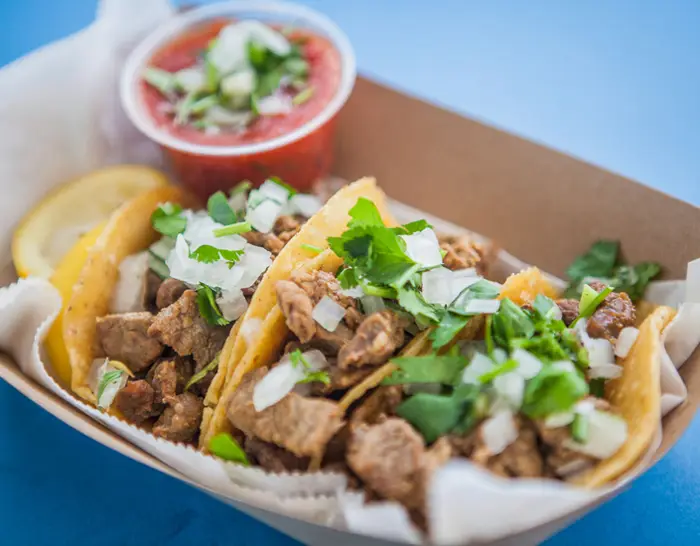 Three carne asada street tacos on corn tortillas